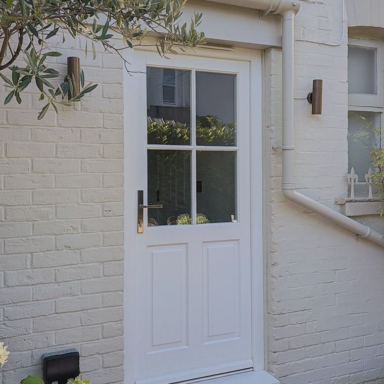 Glazed timber entrance door with four panes over a panelled base and brass ironmongery