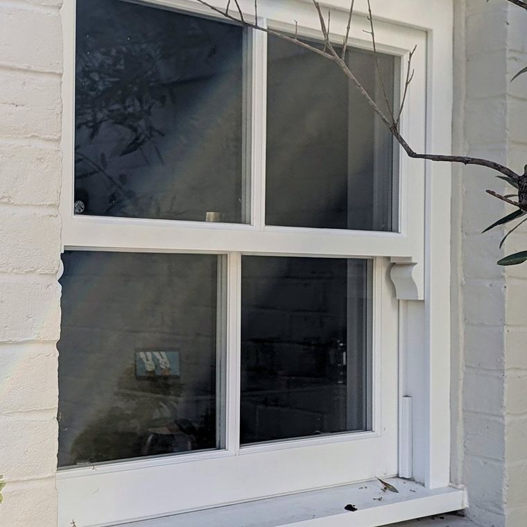 Detail of a timber sash window with a horizontal glazing bar, set under a gauged brick arch